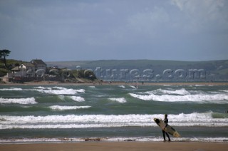 Surfer on beach looking out over swell at Bantham, Devon