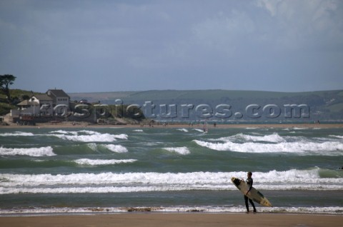 Surfer on beach looking out over swell at Bantham Devon