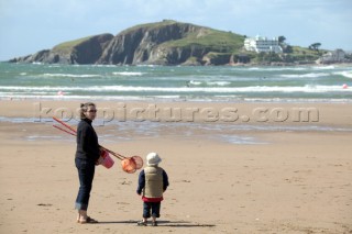 Woman and child with fishing nets on sandy beach at Bantham. Burgh Island in distance.
