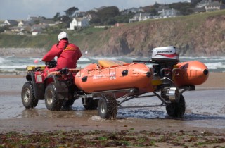 RLNI rescue launch is towed across wet sand at low tide. Bantham, Devon