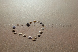 Sea shells laid in a heart shape on wet sand