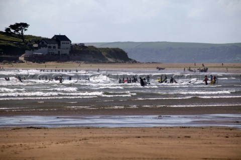 Surfers in waves at low tide Bantham Devon