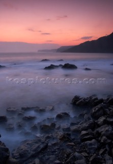 Motion effect of water lapping on shore under pink sky