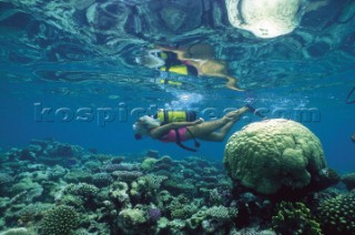 Girl scuba diving over shallow reef