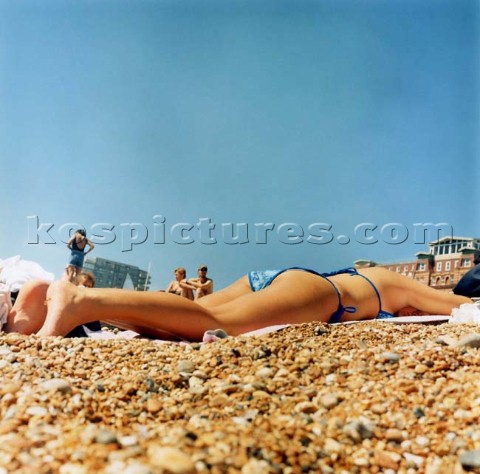 Girl in bikin lying on pebble beach under clear blue sky Brighton