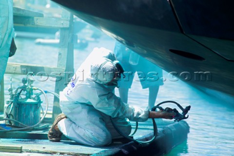 Shipyard workers sparying Awlgrip paint onto the hull of a superyacht