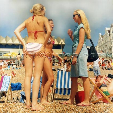 Three girls standing on a crowded Brighton Beach