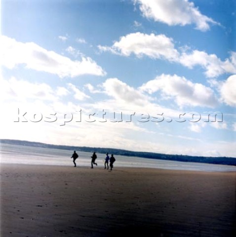 People running along wet sand on the beach at Swansea Wales