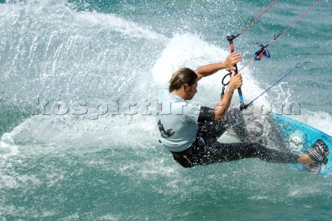 Kitesurfer carving through wave in strong winds