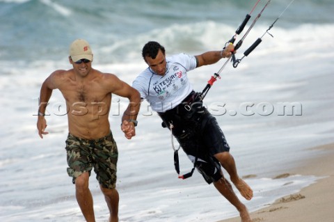 Kitesurfer is pulled pulled along beach by friend