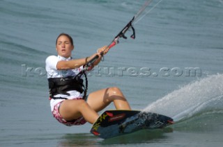 Female Kitesurfer carving through flat water in strong winds