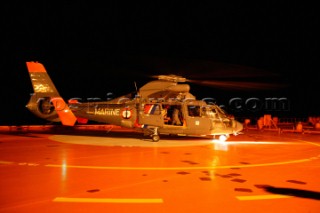 French Navy Coastguard helicopter on helipad. Men in survivial suits on deck of supertanker.
