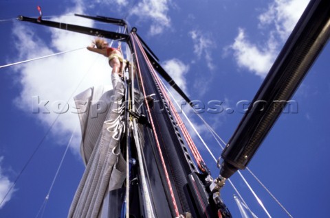 Female professional crew member climbing the mast of a superyacht to perform maintenance and cleanin