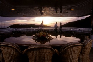 Evening relaxing romantic couple onboard a superyacht in the dining area in the sunset