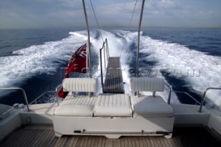 Stern of a motor yacht at speed showing wash and red British ensign flag