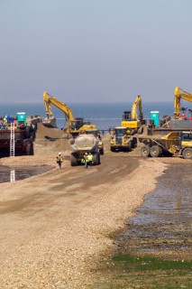 Sea defence building in whitstable kent raising the level of the beach some meters to counter rising sea level and erosion, barge at the low tide marke with the beach infill being transport by trucks