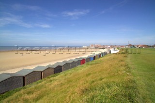 Part of the beach front of Minnis Bay in Kent England edged by bathing huts with a breakwater in view
