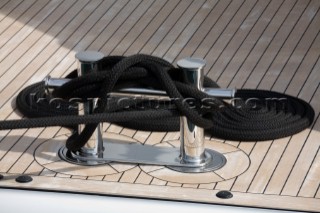 Rope and dock line around a stainless steel cleat on the teak stern deck of a superyacht