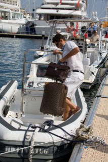 Professional crew man in whites uniform carries luggage aboard a superyacht rib tender having welcomed the owner