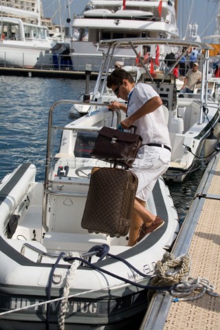 Professional crew man in whites uniform carries luggage aboard a superyacht rib tender having welcom