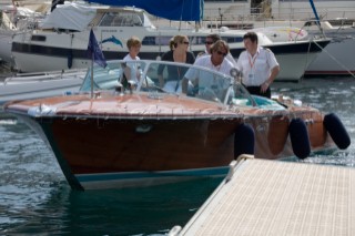 Riva tender driven by a professional crew man in whites uniform arriving with guests in port