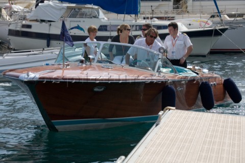 Riva tender driven by a professional crew man in whites uniform arriving with guests in port