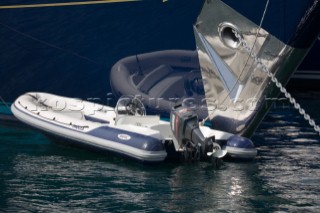 Reflection of a rib tender alongside the anchor and chain of a dark blue hulled superyacht
