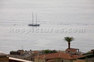 Classic schooner motoring under power across a calm Mediterranean Sea with palm tree