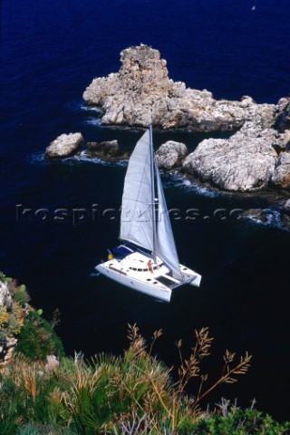 Sicily Italy A lady lounges on the deck of a catamaran as it sails into a channel