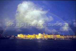 A rainbow creates a dome effect over the village of Saint Tropez with the waterfront buildings bathed in brilliant sunshine