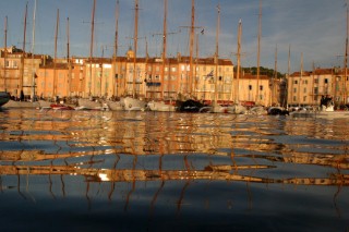 Early morning in the port at Saint Tropez view looking at the buildings on the waterfront from the waterline through the masts of boats moored in the harbour