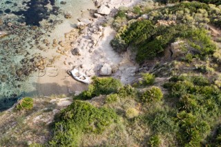 Aerial view of a lone dinghy nestling on a sandy beach of an island