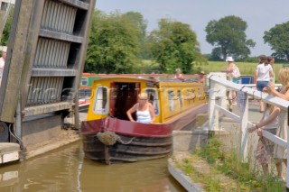 Woman on narrow boat passing through Wrenbury lift bridge on the Llangollen canal,Wrenbury,Cheshire,England.July 2006.