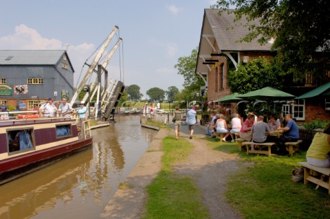 People on narrow boat passing through Wrenbury lift bridge outside the Dusty Miller pub on the Llang