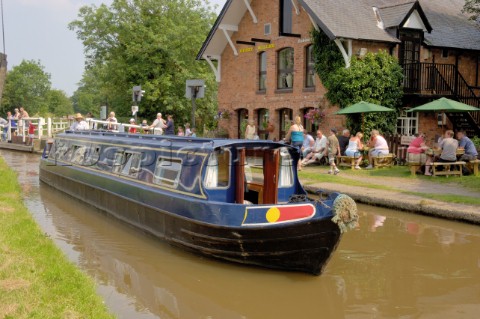 People on narrow boat passing through Wrenbury lift bridge outside the Dusty Miller pub on the Llang