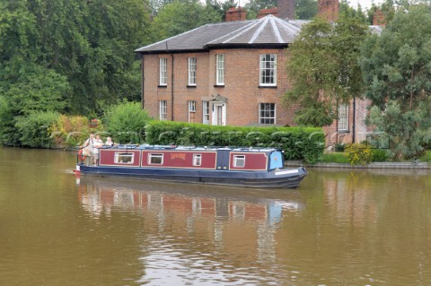 People on narrow boat passing house  on the Llangollen canal at EllesmereShropshireEngland