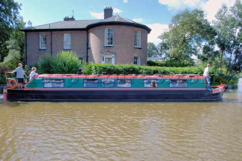 People on narrow boat passing house  on the Llangollen canal at EllesmereShropshireEngland
