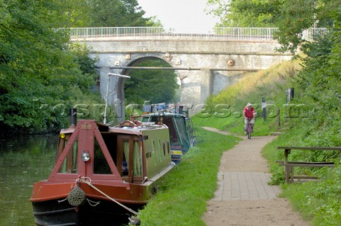 Narrow boats and cyclist by bridge 14 on the Shropshire Union canal at BrewoodStaffordshireEnglandSe