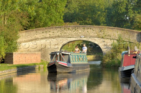 Couple on narrowboat passing under bridge 18 at Wheaton Aston on the Shropshire Union canalStaffords