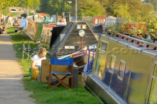 Woman painting on towpath near moored narrow boats on the Shropshire Union canal at Wheaton Aston,Staffordshire,England.September 2006.