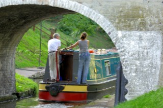 Couple on narrow boat passing under Tavern bridge number 19 on the Shropshire Union canal at Wheaton Aston,Staffordshire,September 2006.