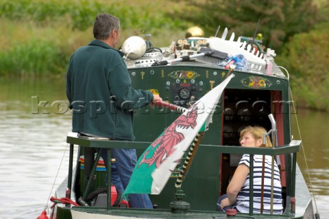 Couple flying the Welsh flag on a  narrow boat on the Llangollen canal at BettisfieldClwydWalesSepte