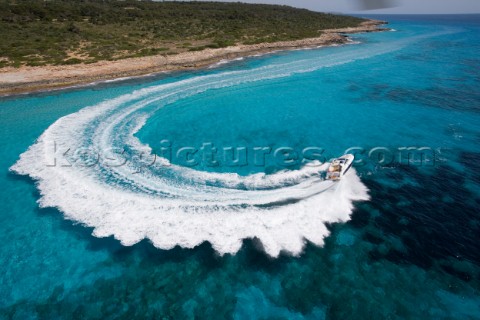 A power boat performs a 180 turn by the shore creating a doily effect wash