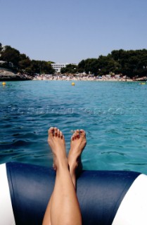 Away from the crowd. Relaxing in a dinghy in a bay flanked by a crowded beach