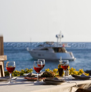 Dinner table set with filled wine glasses with power boat seen in background