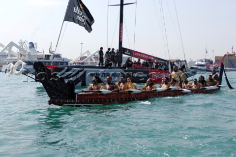 A Maori war canoe Waka leads Emirates Team New Zealand NZL92 out of the harbour for the first day of