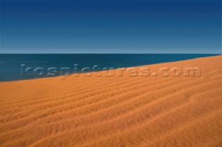 Huge red sand dunes meet the sea