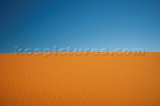 Deep coloured sand dune meets a clear blue sky