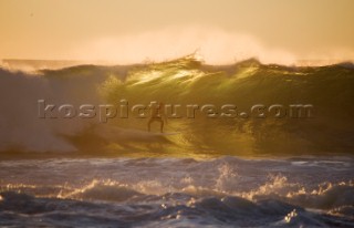 Surfer at dusk on a large wave close to the shore