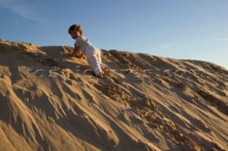 Little girl playing on sand dunes on a sandy beach in Tarifa, Spain, near Gibraltar. (Model released)
